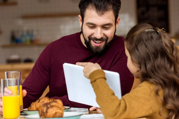 Figlia mostrando qualcosa sul tablet al padre nel caffè — Foto stock