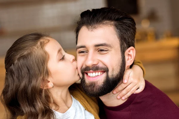 Retrato de hija besando sonriente padre en la cafetería - foto de stock