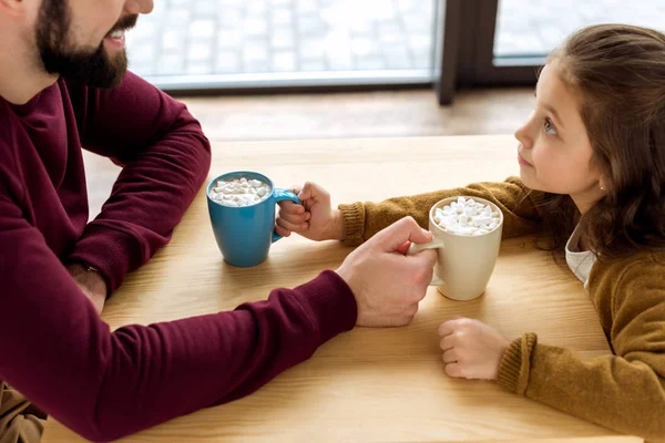 Cropped image of happy daughter and father changing their cups of cacao with marshmallow — Stock Photo