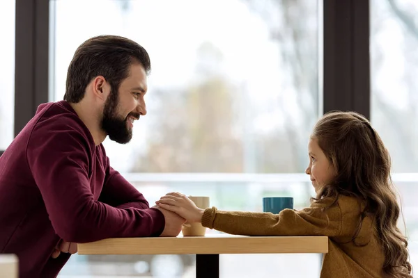 Pai e filha sentados no café e de mãos dadas — Fotografia de Stock