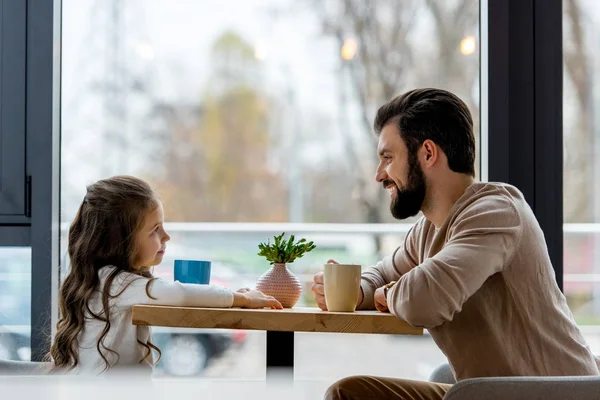 Happy father and daughter sitting in cafe and looking at each other — Stock Photo