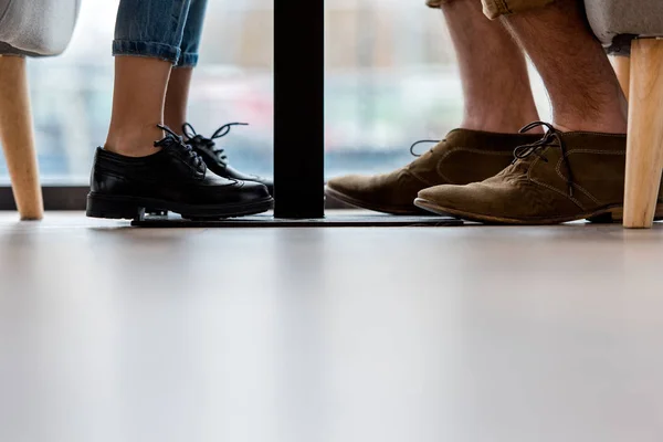 Imagen recortada de padre e hija piernas debajo de la mesa - foto de stock