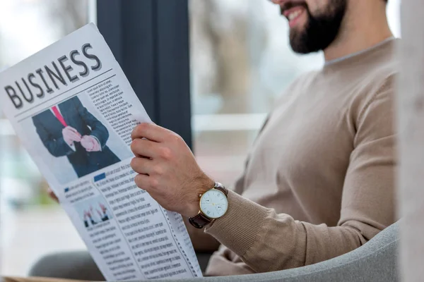 Imagem recortada de um empresário sorridente sentado no café e lendo jornal — Fotografia de Stock