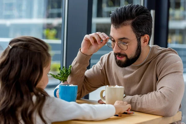 Father and daughter sitting in cafe with cups of cacao with marshmallow — Stock Photo