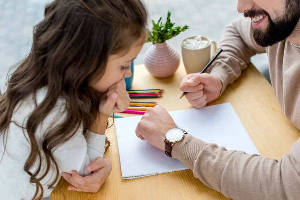 Recortado imagen de padre sosteniendo lápiz y mostrando reloj a hija - foto de stock