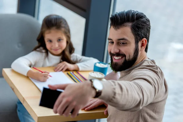 Smiling father taking selfie of him and daughter in cafe — Stock Photo