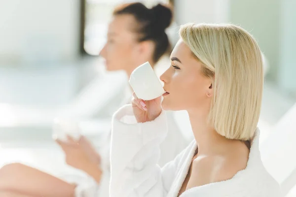 Beautiful young women drinking coffee at spa center — Stock Photo