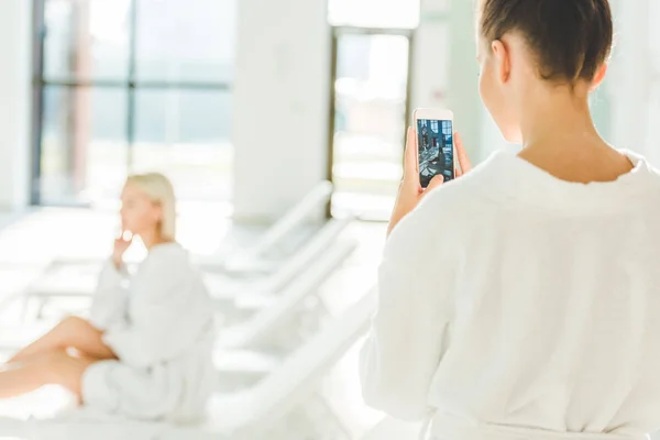 Жінка фотографує свого друга в спа-центрі зі смартфоном — стокове фото