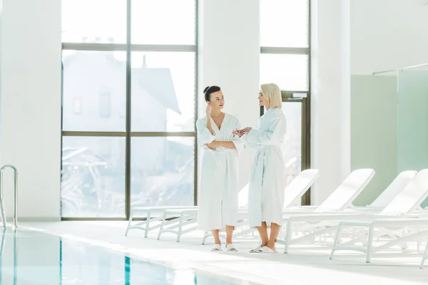 Schöne junge Frauen in Bademänteln unterhalten sich im Wellnesszentrum — Stockfoto