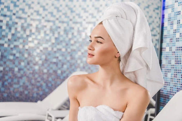 Femme séduisante réfléchie avec serviette sur la tête au spa — Photo de stock
