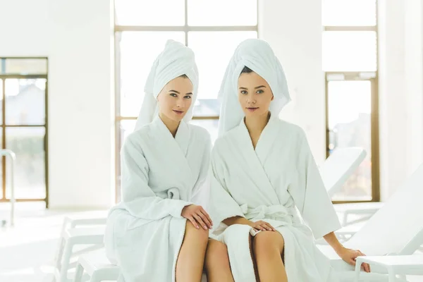 Hermosas mujeres jóvenes en albornoces y toallas en la cabeza en el centro de spa - foto de stock