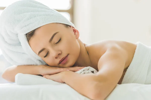 Hermosa mujer joven relajándose en la mesa de masaje en el salón de spa - foto de stock
