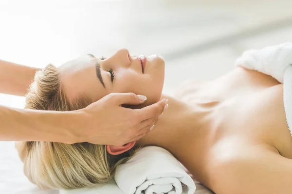 Sonriente joven mujer teniendo masaje facial en el salón - foto de stock