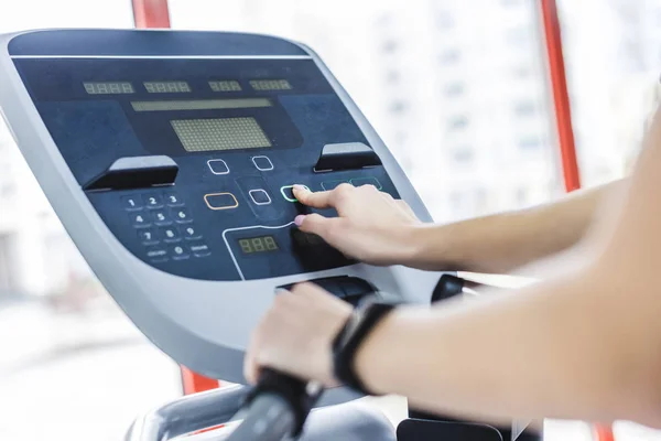 Cropped shot of woman setting up elliptical machine at gym — Stock Photo