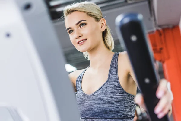 Nahaufnahme einer Frau, die im Fitnessstudio an einem Crossgerät trainiert — Stockfoto