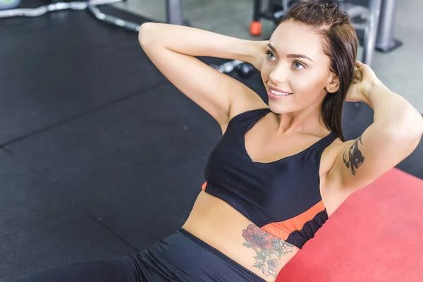 Молода красива жінка робить абс чіпси на йога мат в спортзалі і посміхається — стокове фото