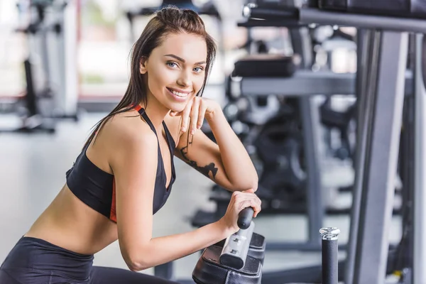 Молода приваблива жінка розслабляється в спортзалі після тренування — стокове фото