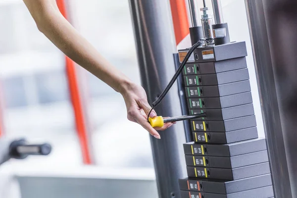 Cropped shot of woman adding weight bars on gym machine — Stock Photo