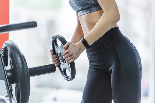 Cropped shot of sportive woman adding weight plate to gym machine — Stock Photo