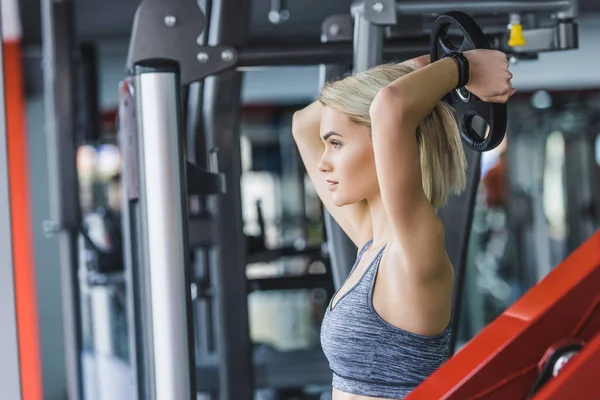 Young woman working out with weight plate at gym — Stock Photo