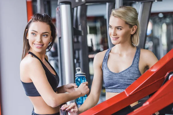 Mulheres esportivas sorridentes relaxando após o treino no ginásio — Fotografia de Stock