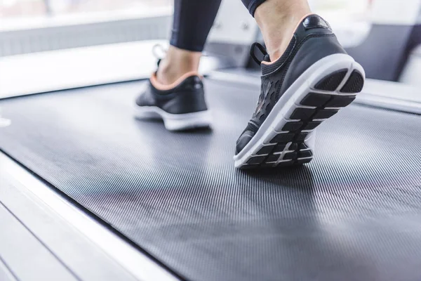 Cropped shot of woman in jogging sneakers running on treadmill — Stock Photo