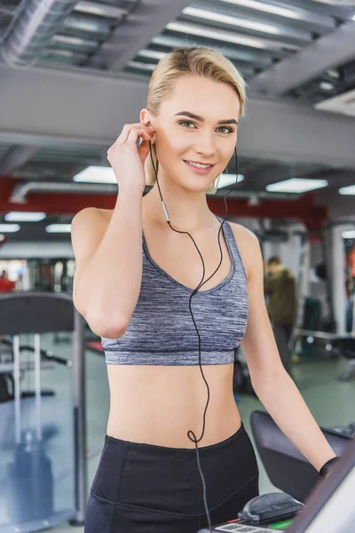 Приваблива молода жінка слухає музику з навушниками у спортзалі — стокове фото