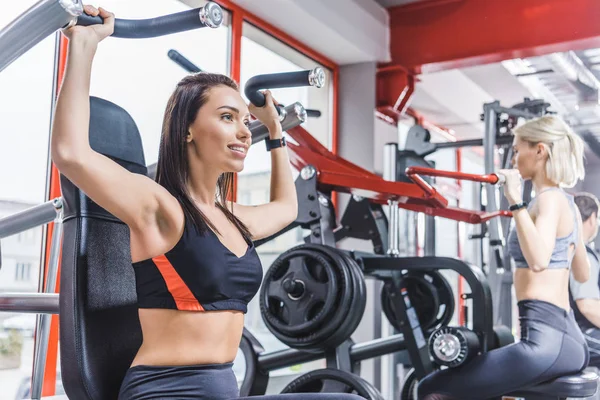 Beautiful sportive women working out with gym machines — Stock Photo