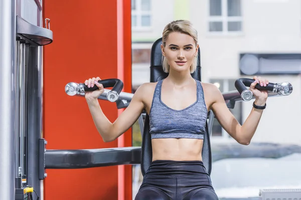 Young sportive woman working out with gym machine — Stock Photo