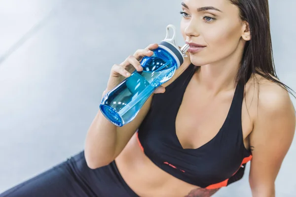 Молодая спортивная женщина пьет воду после тренировки — стоковое фото