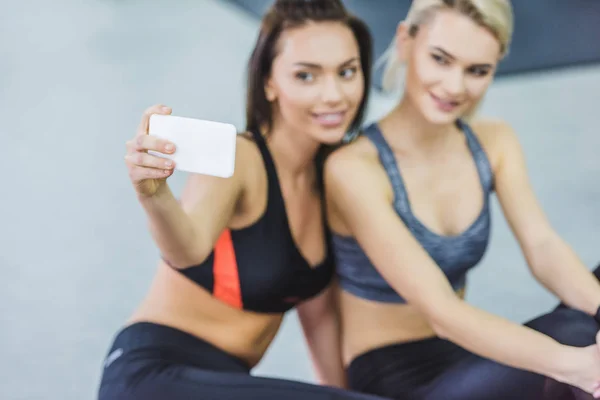 Primer plano de las mujeres jóvenes deportivas que toman selfie en el gimnasio - foto de stock