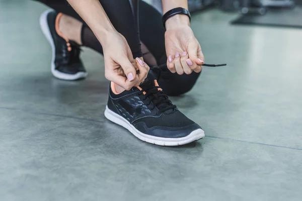 Recortado tiro de mujer atando zapatillas de deporte antes de entrenar - foto de stock