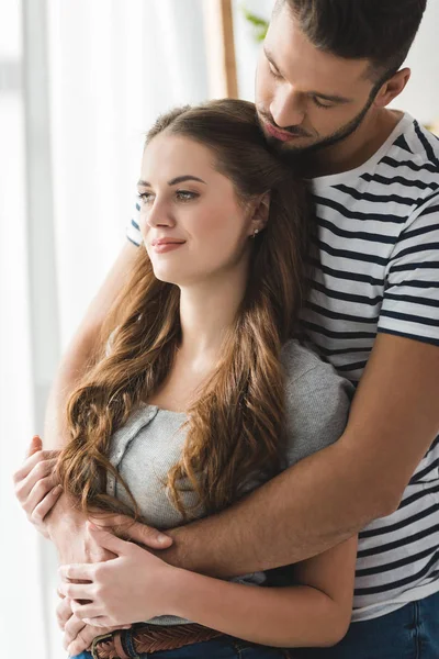 Beautiful young couple embracing near window — Stock Photo