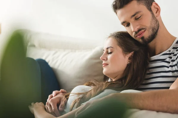 Jeune couple aimant dormir sur le canapé et embrasser à la maison — Photo de stock