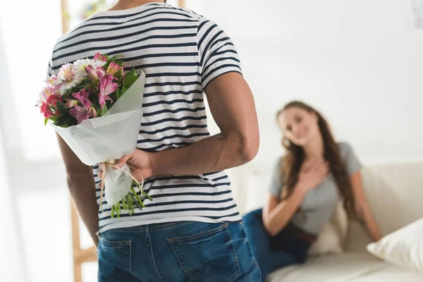 Colpo ritagliato di giovane uomo nascondendo bouquet dietro la schiena per presentarlo alla fidanzata — Stock Photo