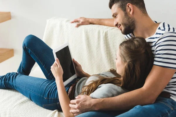 Jeune couple utilisant la tablette ensemble sur le canapé à la maison — Photo de stock