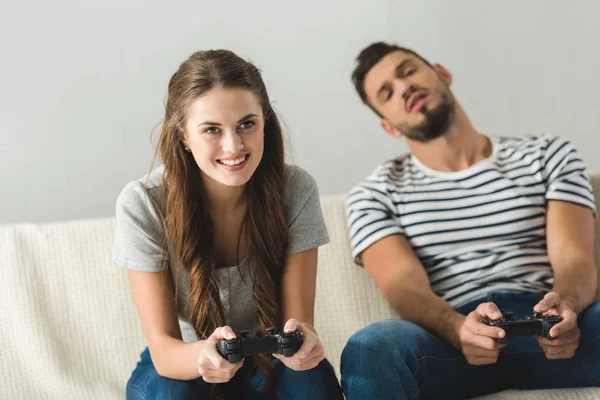 Емоційна молода пара грає в ігри з геймпадами вдома — стокове фото