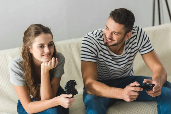 Belo jovem casal jogar jogos com gamepads em casa — Fotografia de Stock