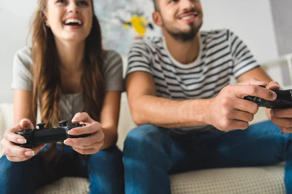 Primer plano de la joven pareja jugando juegos con gamepads en casa - foto de stock