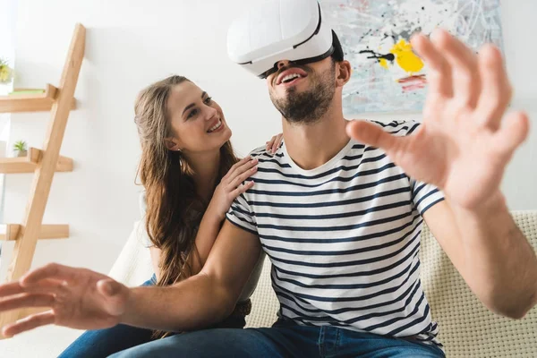 Donna guardando il suo eccitato giovane fidanzato in auricolare vr — Foto stock