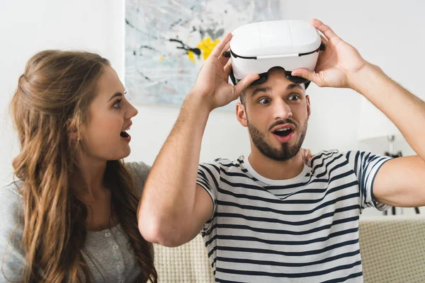 Woman looking at her shocked young boyfriend in vr headset — Stock Photo