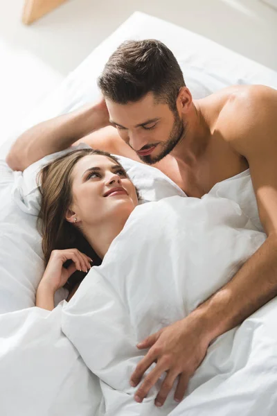 Sorridente giovane uomo abbracciare fidanzata da dietro a letto al mattino — Foto stock