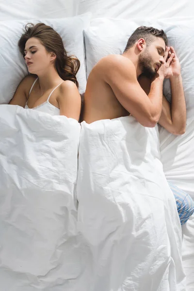 Vista superior de pareja joven durmiendo en la cama espalda con espalda - foto de stock