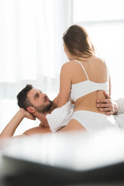 Jeune homme embrassant sa petite amie en sous-vêtements blancs au lit le matin — Photo de stock
