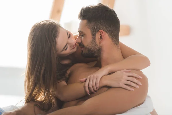 Beautiful young woman embracing boyfriend from behind and kissing — Stock Photo