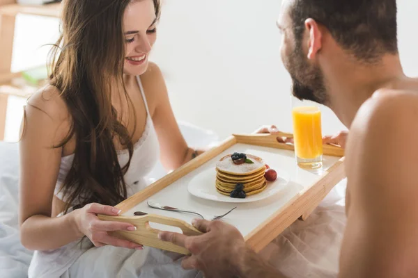 Homem dando café da manhã na cama para bela namorada feliz — Fotografia de Stock