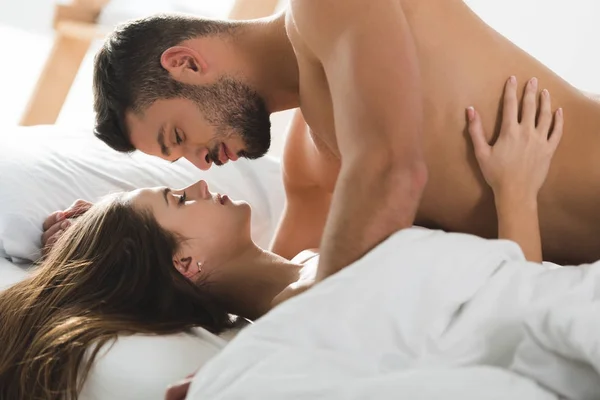 Passionné jeune couple câlins au lit le matin — Photo de stock
