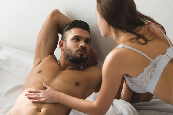Femme touchant son copain torse nu au lit le matin — Photo de stock
