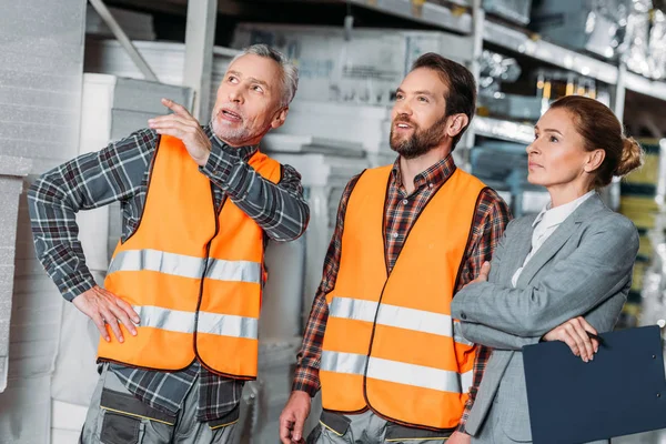 Workers showing storehouse to female inspector — Stock Photo