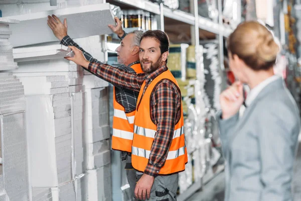 Workers with styrofoam, inspector standing on on foreground in storehouse — Stock Photo